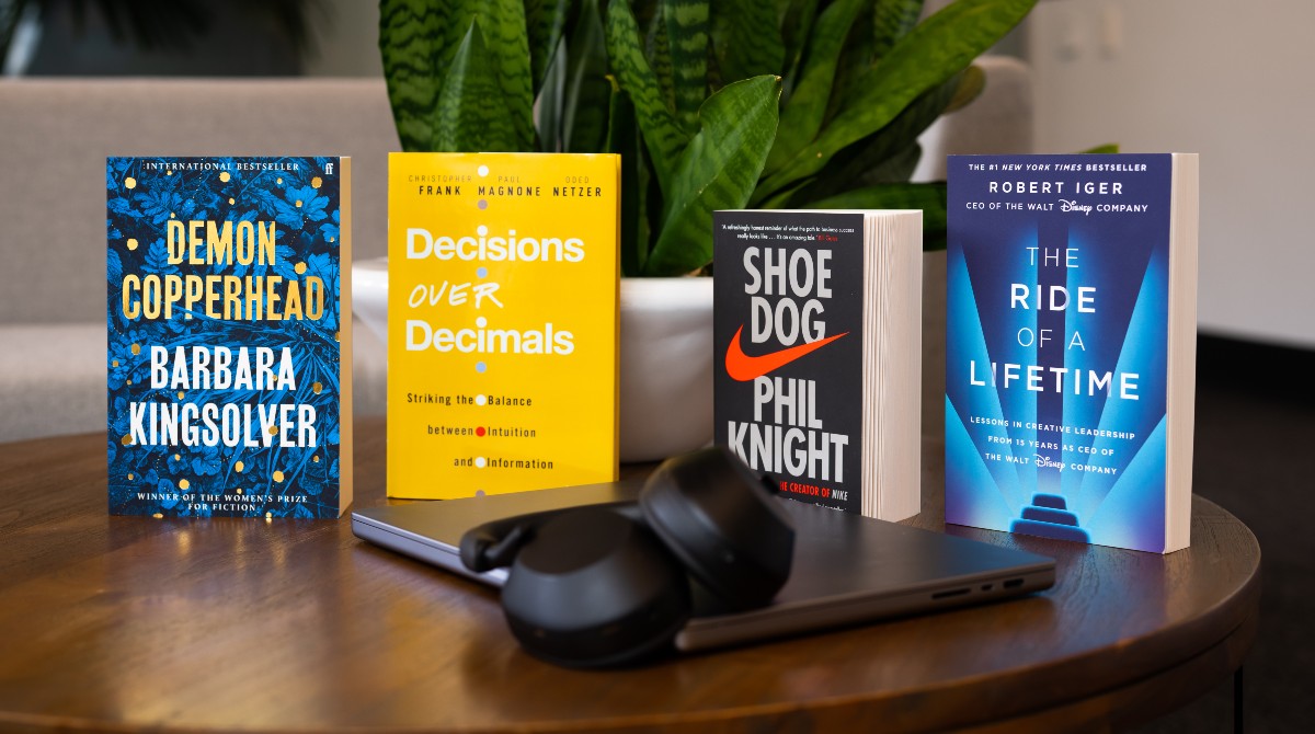 four books, headphones and a laptop on a table